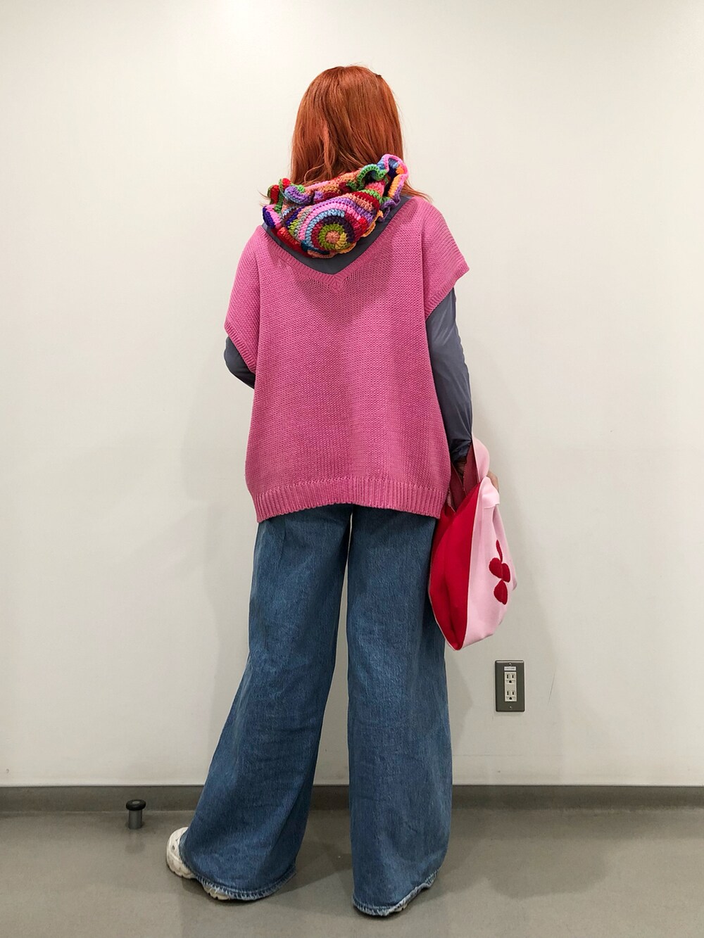 ピンク系のトートバッグ、ブルー系のデニムパンツ、ピンク系のベストを着用したレディースの冬コーディネートの2枚目の写真