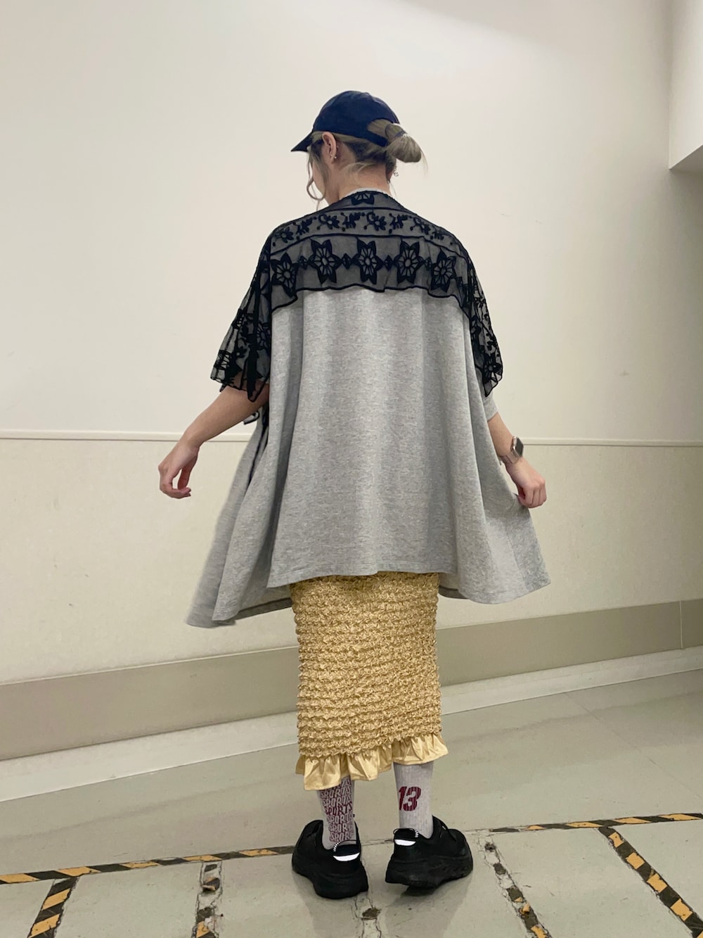 ブラック系のスニーカー、グレー系のTシャツ/カットソー、イエロー系のスカートを着用したレディースの春コーディネートの2枚目の写真