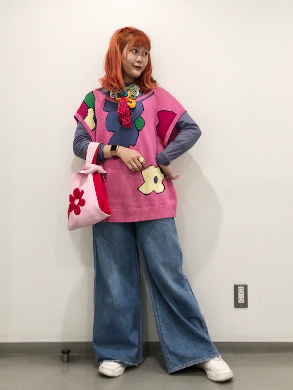 ピンク系のトートバッグ、ブルー系のデニムパンツ、ピンク系のベストを着用したレディースの冬コーディネートの3枚目の写真