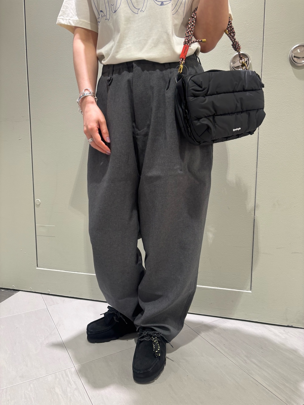 グレー系のスラックス、ブラック系のショルダーバッグ、ブラック系のモカシン/デッキシューズを着用したレディースの夏コーディネートの3枚目の写真