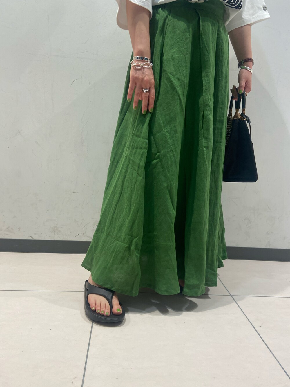 ブラック系のサンダル、ホワイト系のTシャツ/カットソー、ブラック系のかごバッグを着用したレディースの夏コーディネートの3枚目の写真