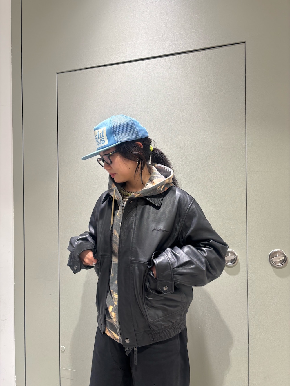 ブラウン系のパーカー、ブラック系のブルゾンを着用したレディースの春コーディネートの2枚目の写真