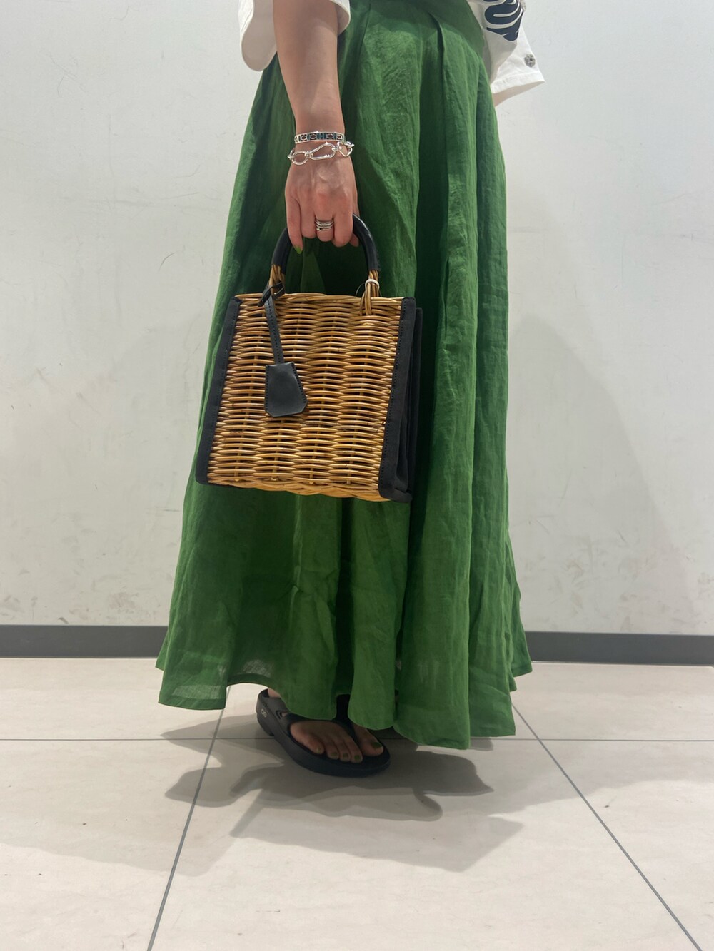 ブラック系のサンダル、ホワイト系のTシャツ/カットソー、ブラック系のかごバッグを着用したレディースの夏コーディネートの2枚目の写真