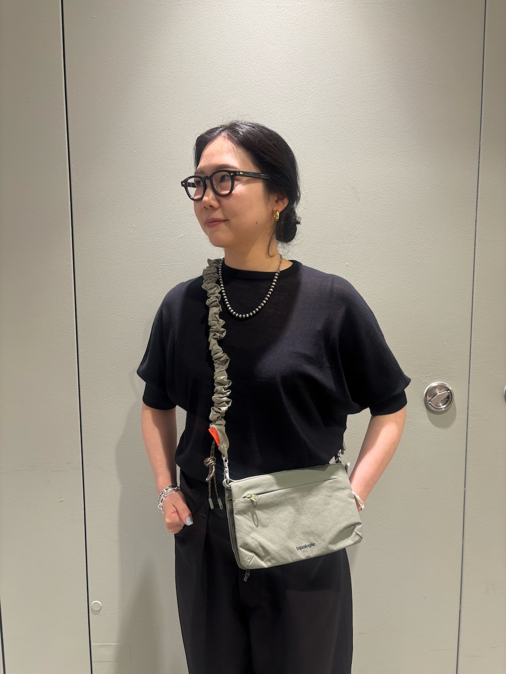 「夏、ショルダーバッグ、ブラックコーデ、BEAVER、ワイドパンツ、ビルケンシュトック、ボストン、黒ニット、黒Tシャツ、BEAVER名古屋」｜「TopologieのTopologie/トポロジー Bungee Strap バンジーストラップ【ストラップ単体】（スマホグッズ、ベージュ系）」を使った、小林さん（レディース・155cm）の春コーディネートの3枚目の写真