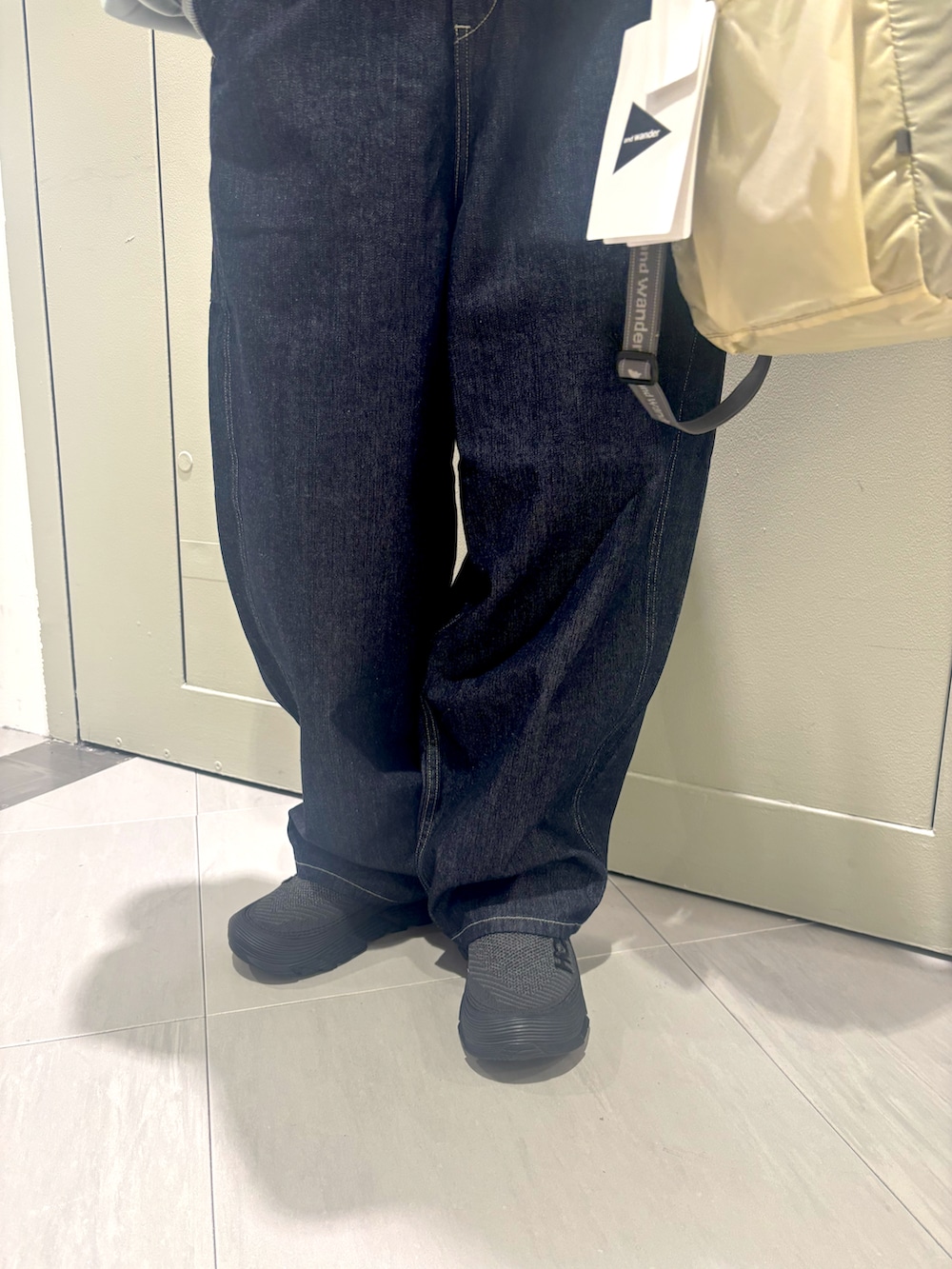 ブラック系のスニーカー、ブルー系のデニムパンツ、ホワイト系のトートバッグを着用したレディースの冬コーディネートの3枚目の写真