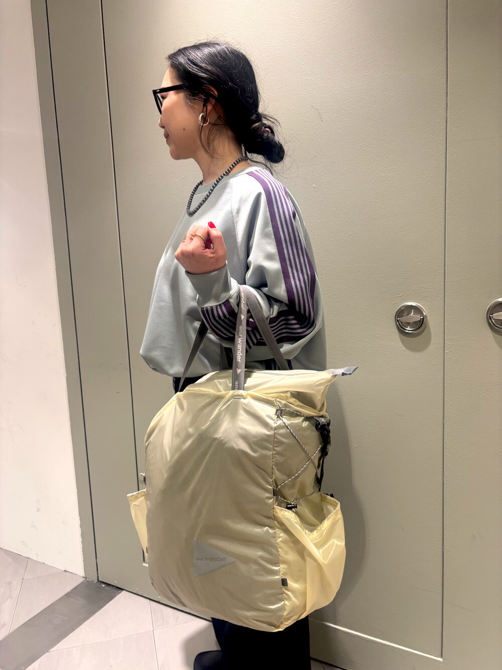 ブラック系のスニーカー、ブルー系のデニムパンツ、ホワイト系のトートバッグを着用したレディースの冬コーディネートの2枚目の写真