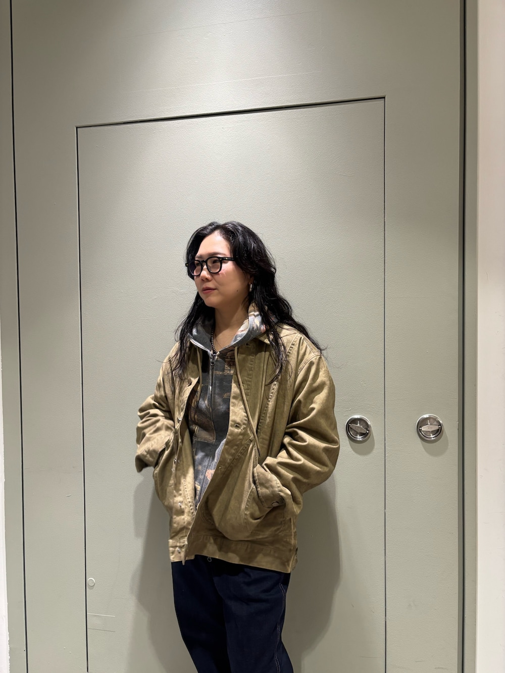 イエロー系のブルゾン、ブラウン系のスウェットパンツ、ブルー系のデニムパンツを着用したレディースの冬コーディネートの2枚目の写真