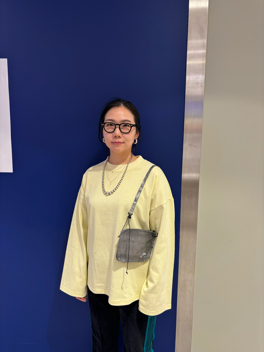 イエロー系のTシャツ/カットソー、ブラック系のサンダル、グレー系のショルダーバッグを着用したレディースの春コーディネートの2枚目の写真