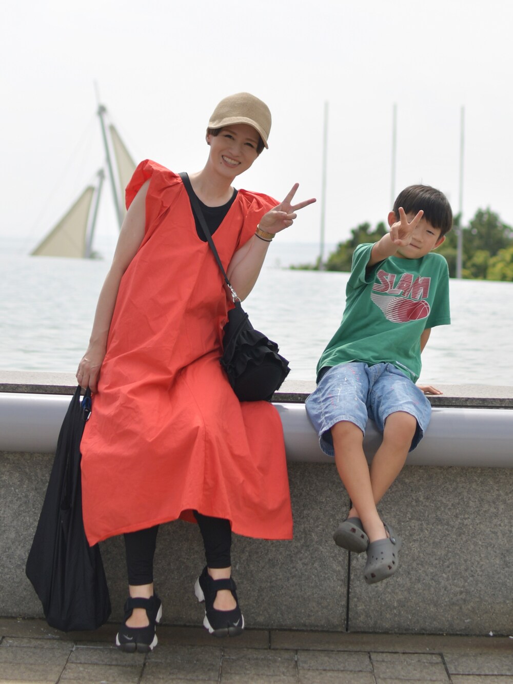 ブラック系のスニーカー、レッド系のワンピースを着用したレディースの秋コーディネートの2枚目の写真