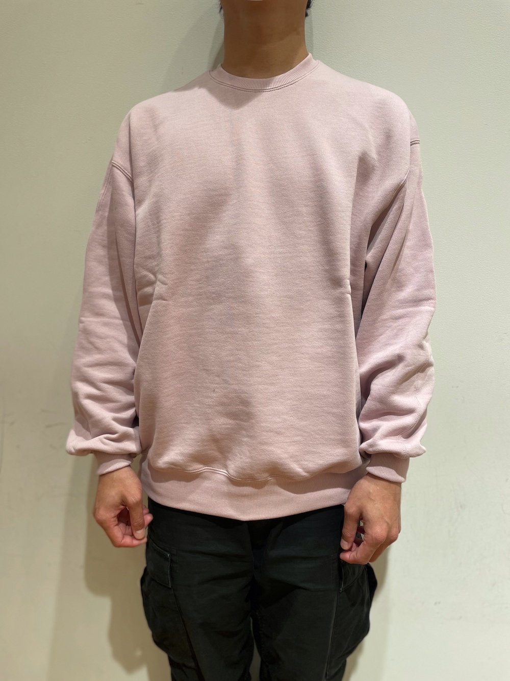 ピンク系のスウェット、ベージュ系のステンカラーコート、ブラック系のカーゴパンツを着用したメンズの冬コーディネートの3枚目の写真