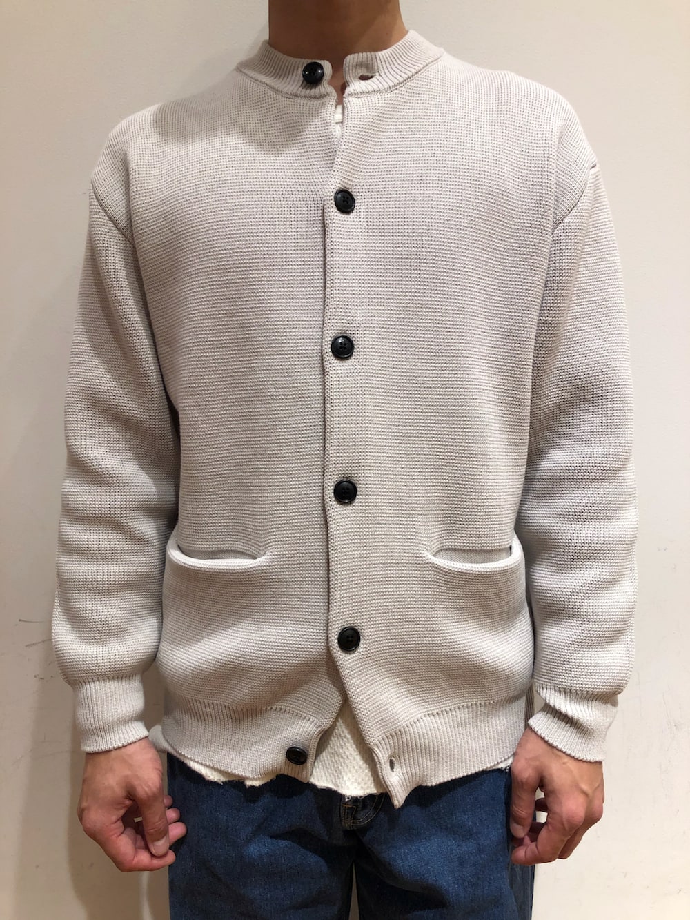 グレー系のニット/セーター、グリーン系のステンカラーコート、ブルー系のシューズを着用したメンズの冬コーディネートの3枚目の写真