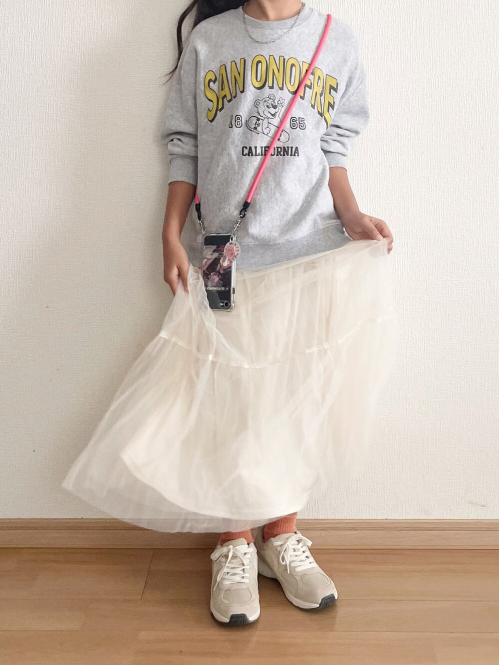 ホワイト系のスカート、ピンク系のスマホグッズを着用したキッズの秋コーディネートの4枚目の写真