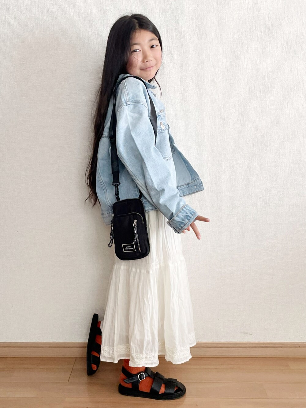 ブルー系のデニムジャケット、ホワイト系のスカート、ブラック系のサンダルを着用したキッズの春コーディネートの2枚目の写真