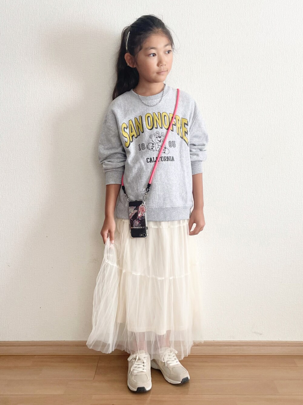 ホワイト系のスカート、ピンク系のスマホグッズを着用したキッズの秋コーディネートの3枚目の写真