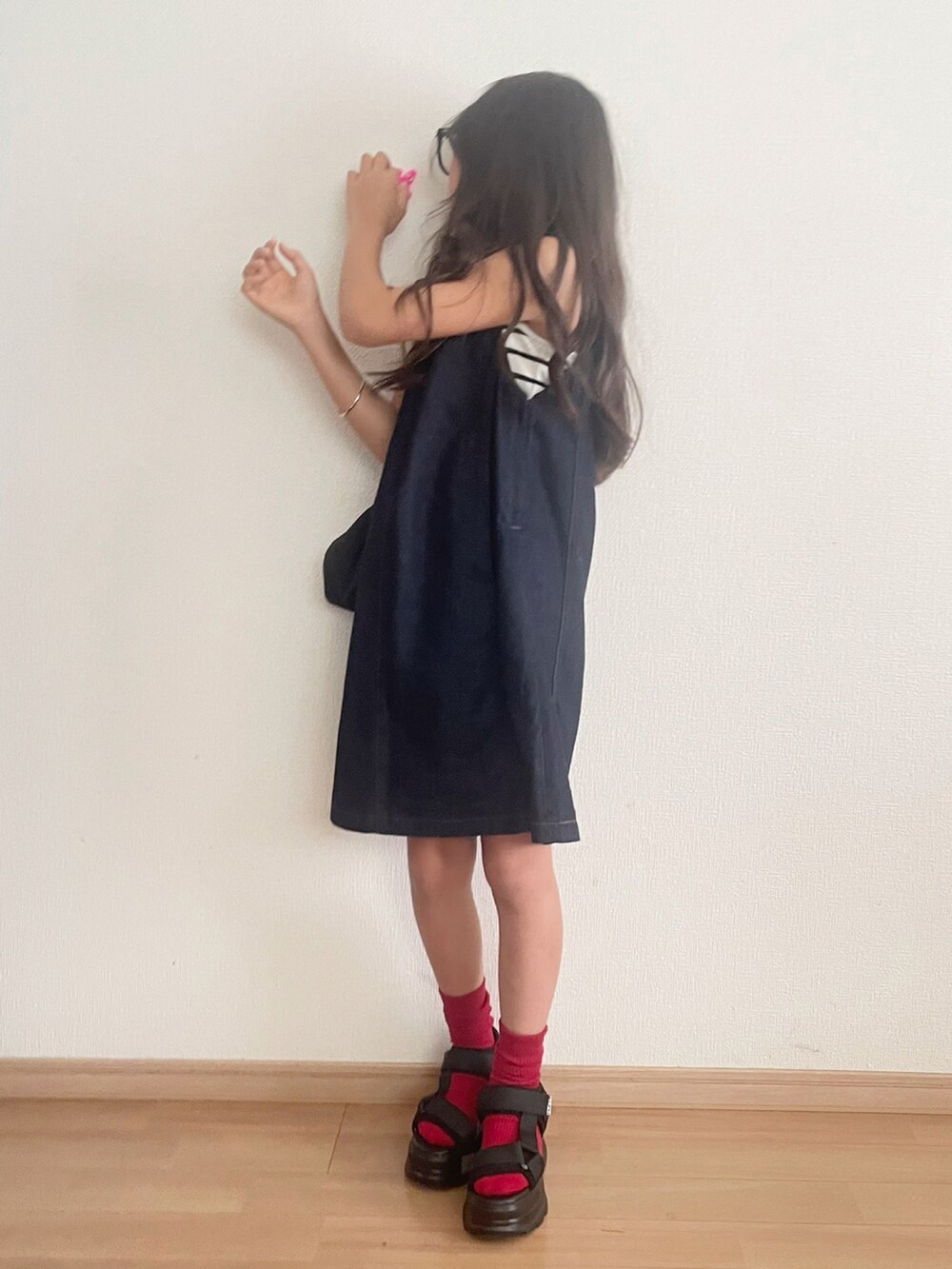 ブラック系のスニーカー、ブルー系のジャンパースカート、ホワイト系のキャミソールを着用したキッズの夏コーディネートの3枚目の写真