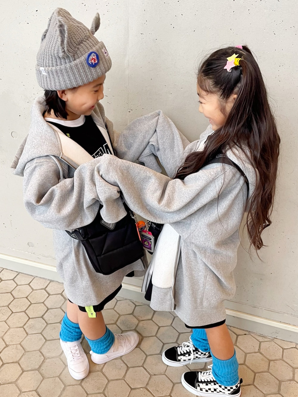 ブラック系のTシャツ/カットソー、ブラック系のショルダーバッグ、グレー系のパーカーを着用したキッズの冬コーディネートの2枚目の写真