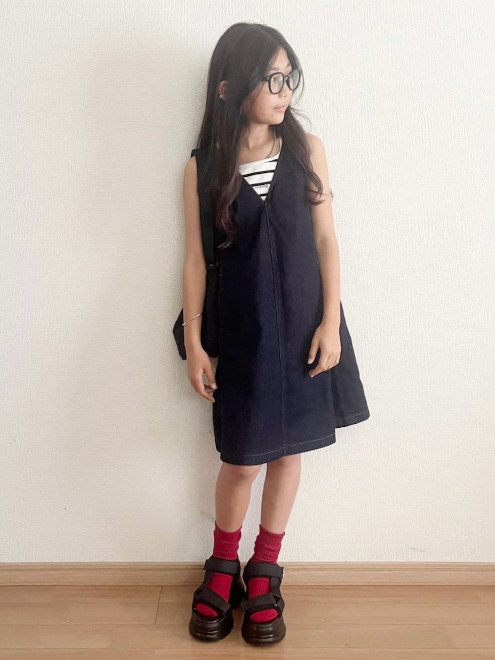 ブラック系のスニーカー、ブルー系のジャンパースカート、ホワイト系のキャミソールを着用したキッズの夏コーディネートの2枚目の写真