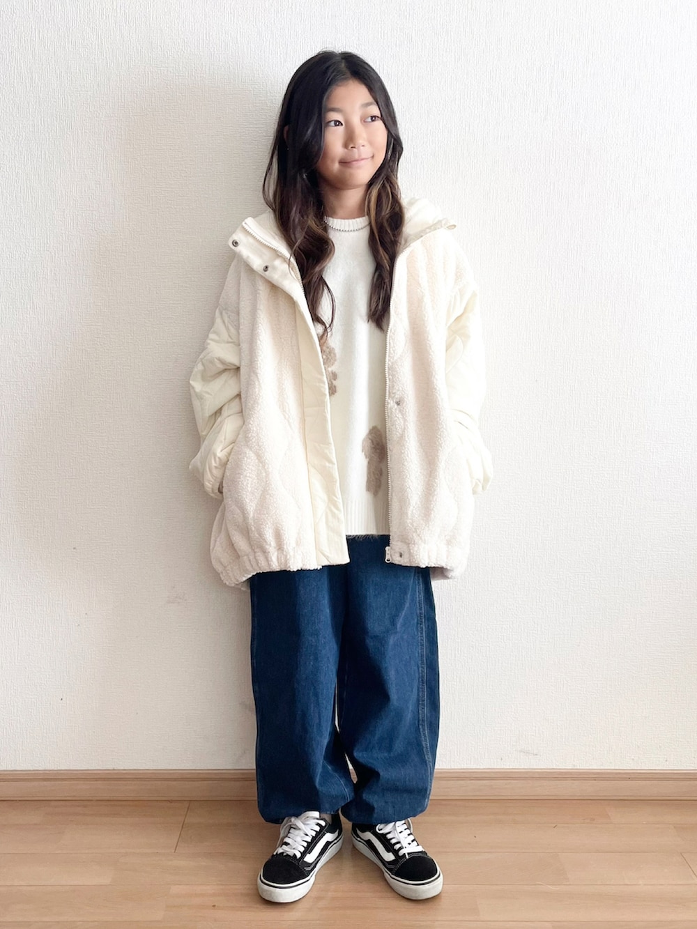 ホワイト系のジャケット/アウター、ホワイト系のニット/セーター、ブルー系のデニムパンツを着用したキッズの秋コーディネートの2枚目の写真