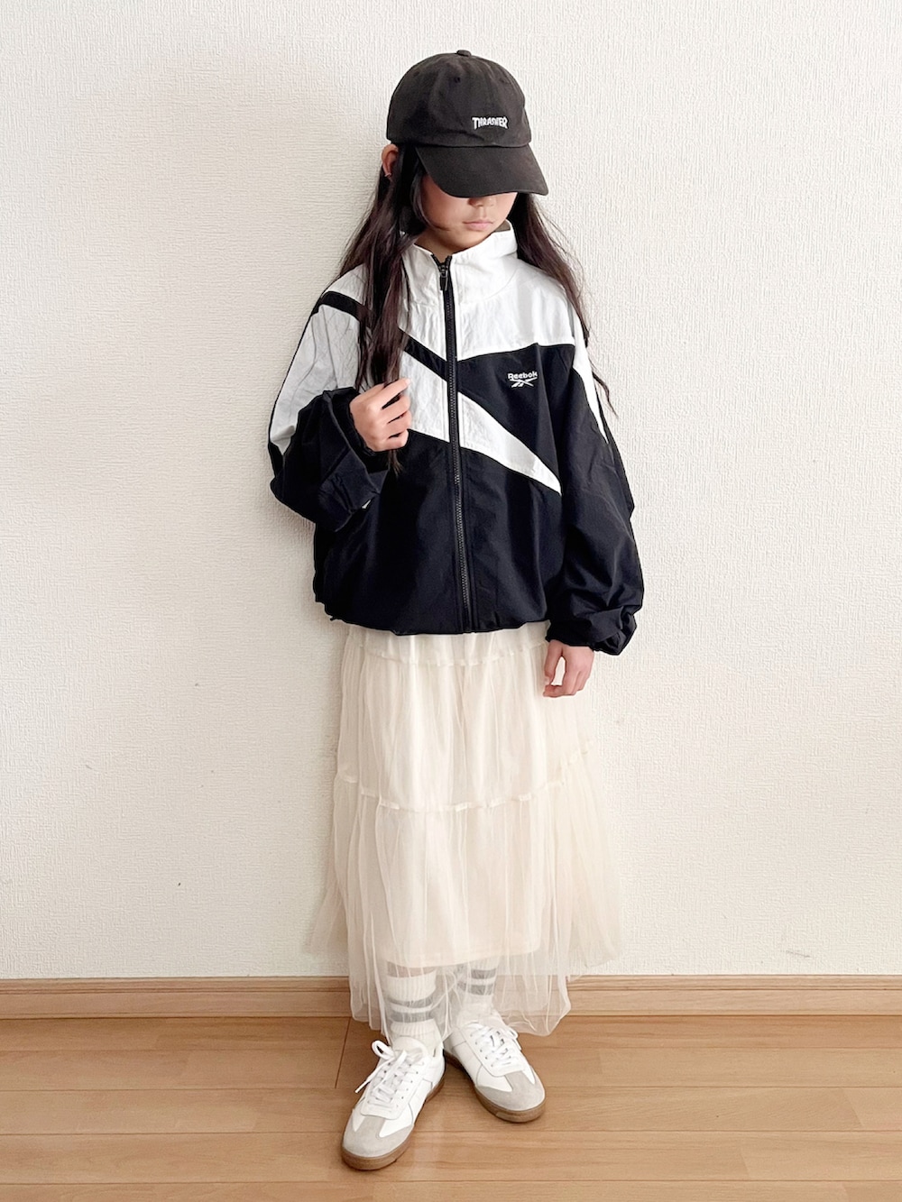 ブラック系のブルゾン、ホワイト系のスカート、ホワイト系のスニーカーを着用したキッズの春コーディネートの2枚目の写真