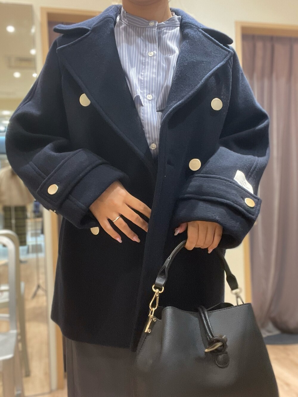 ブラック系のハンドバッグ、グレー系のスカート、ブラック系のシャツ/ブラウスを着用したレディースの秋コーディネートの2枚目の写真