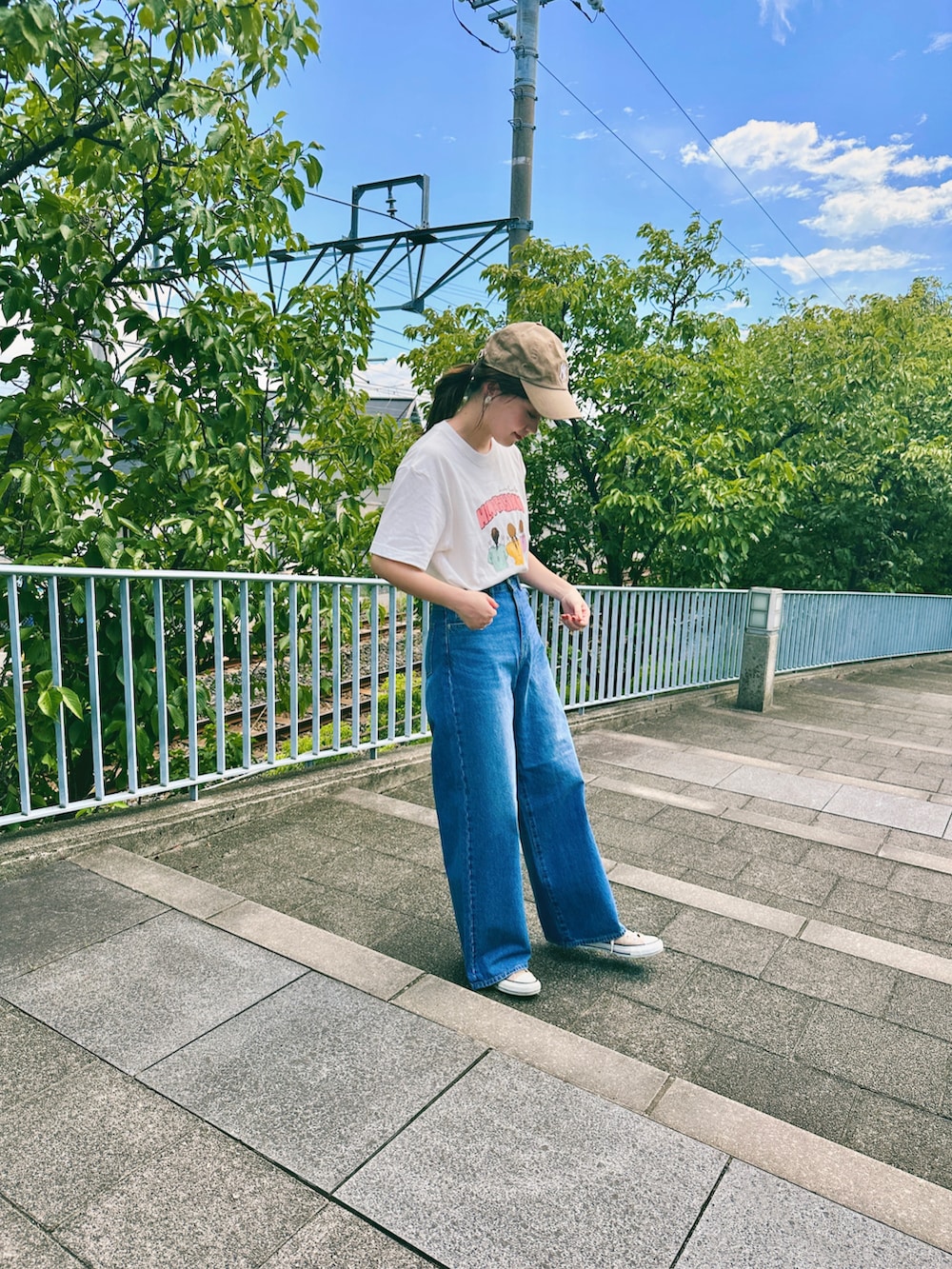 ブルー系のデニムパンツ、ベージュ系のスニーカー、ホワイト系のTシャツ/カットソーを着用したレディースの夏コーディネートの2枚目の写真