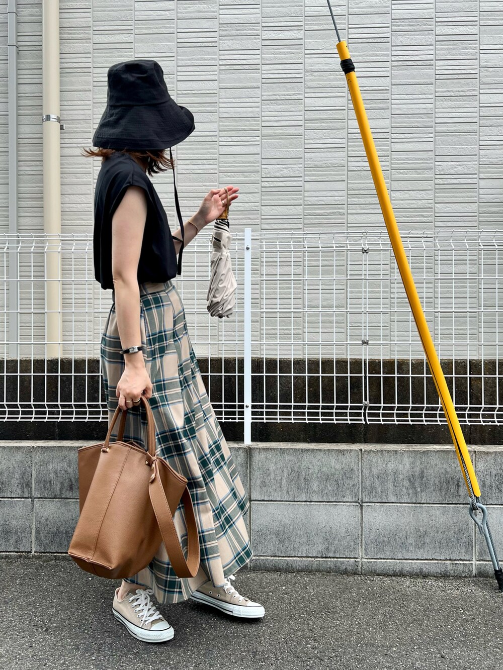 ブラウン系のバッグ、ベージュ系のスカート、ブラック系のトップスを着用したレディースの夏コーディネートの3枚目の写真