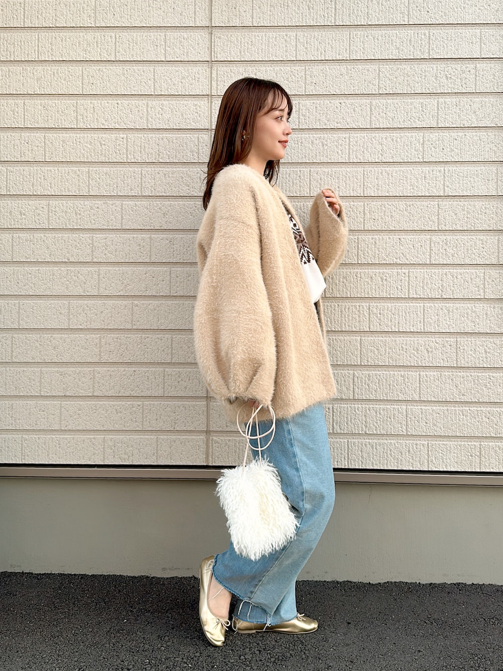 ベージュ系のノーカラーコート、ホワイト系のニット/セーター、ブルー系のデニムパンツを着用したレディースの秋コーディネートの3枚目の写真