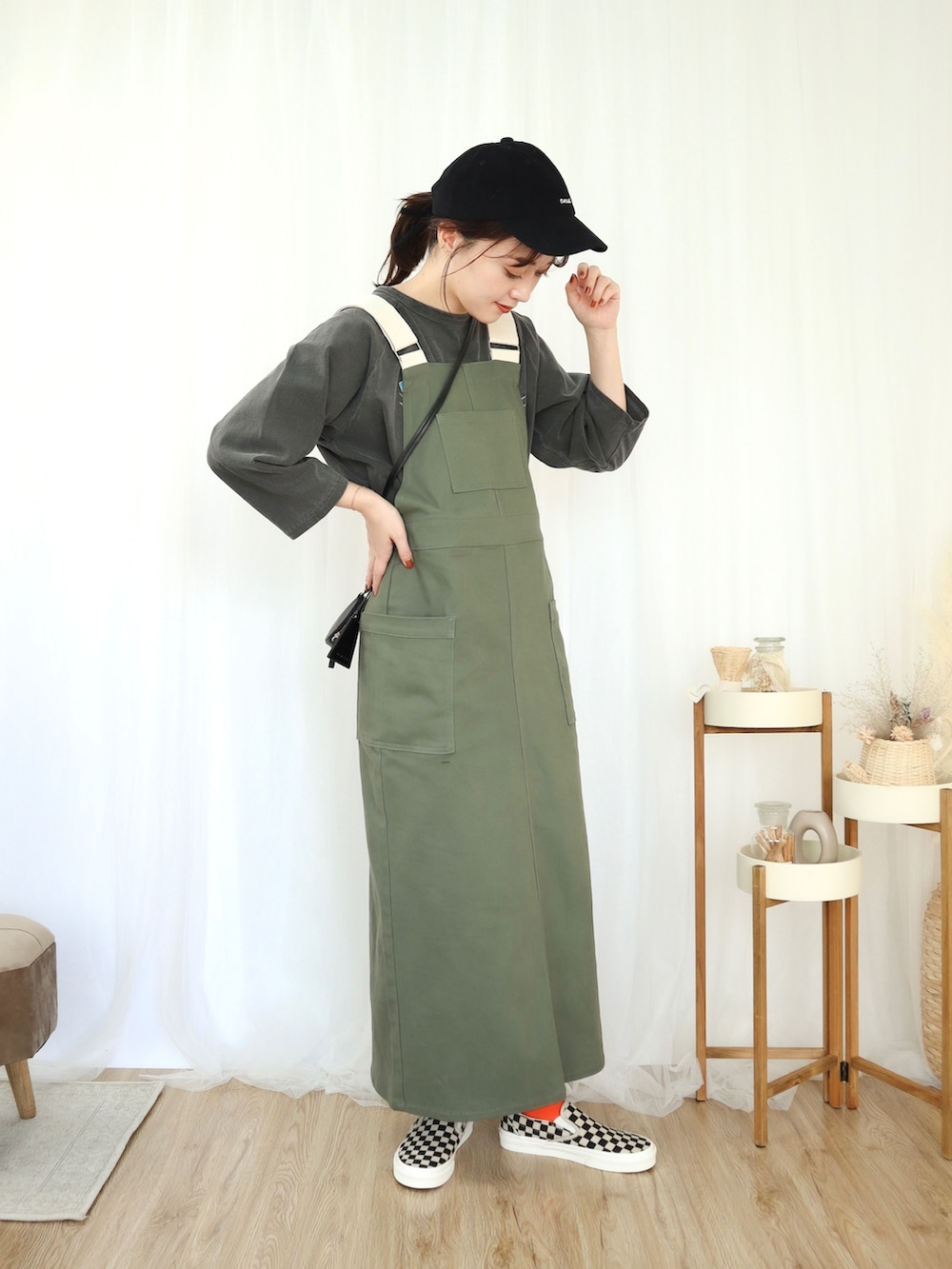 グリーン系のジャンパースカート、ブラック系のダウンベスト、ブラック系のTシャツ/カットソーを着用したレディースの秋コーディネートの2枚目の写真