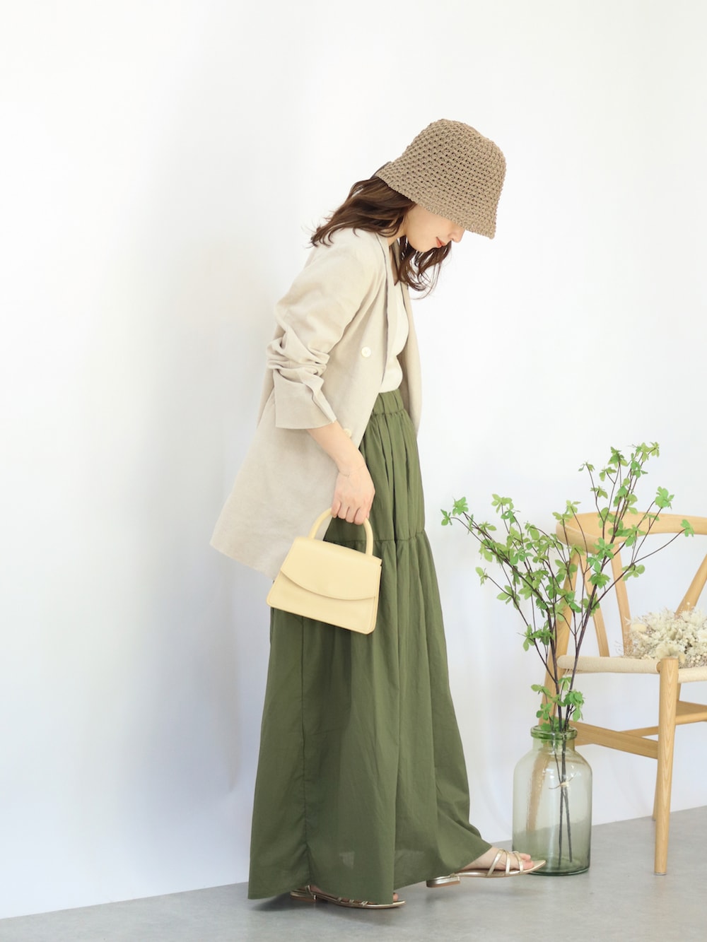 ベージュ系のテーラードジャケット、グリーン系のスカート、ベージュ系のハンドバッグを着用したレディースの夏コーディネートの3枚目の写真