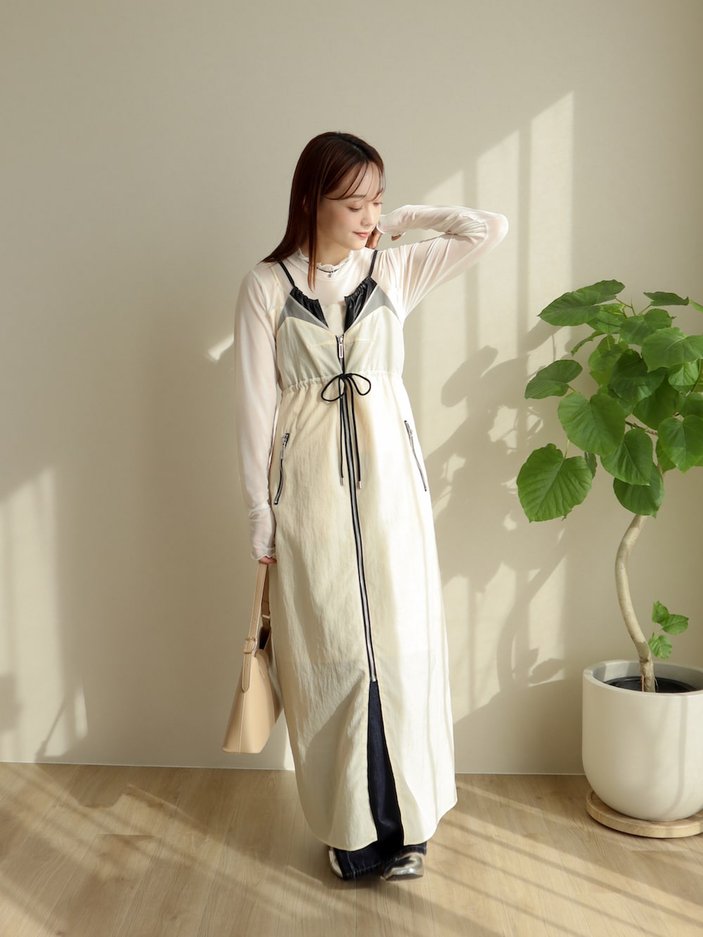 ホワイト系のジャンパースカート、ブルー系のデニムパンツ、シルバー系のパンプスを着用したレディースの冬コーディネートの2枚目の写真