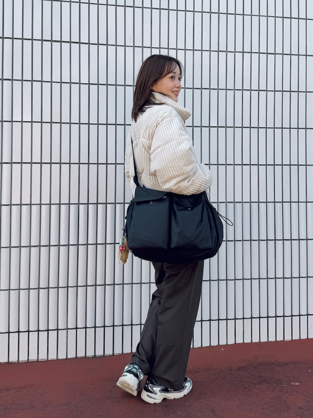 ブラック系のショルダーバッグ、ブラウン系のスラックス、ブラック系のスニーカーを着用したレディースの冬コーディネートの2枚目の写真