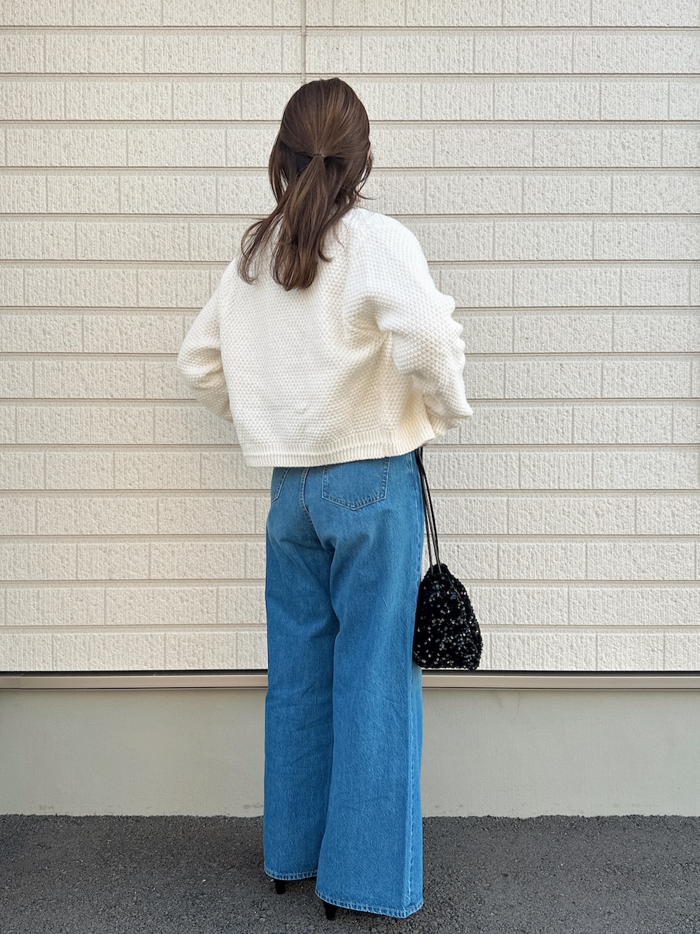 ブルー系のデニムパンツ、ホワイト系のカーディガン/ボレロ、ブラック系のショルダーバッグを着用したレディースの秋コーディネートの3枚目の写真