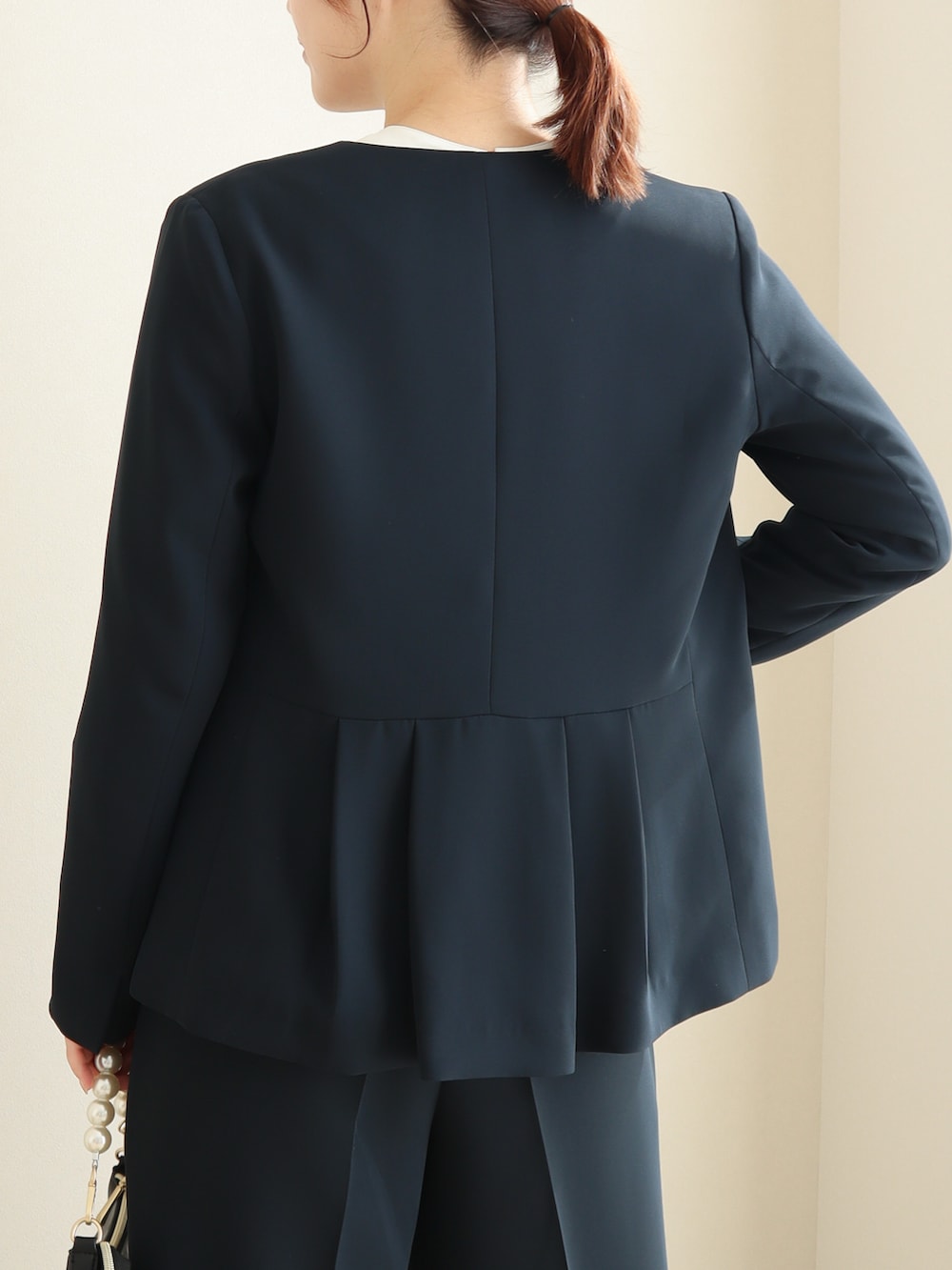 ブルー系のスーツセット、ピンク系のパンプス、ブラック系のバッグを着用したレディースの冬コーディネートの3枚目の写真