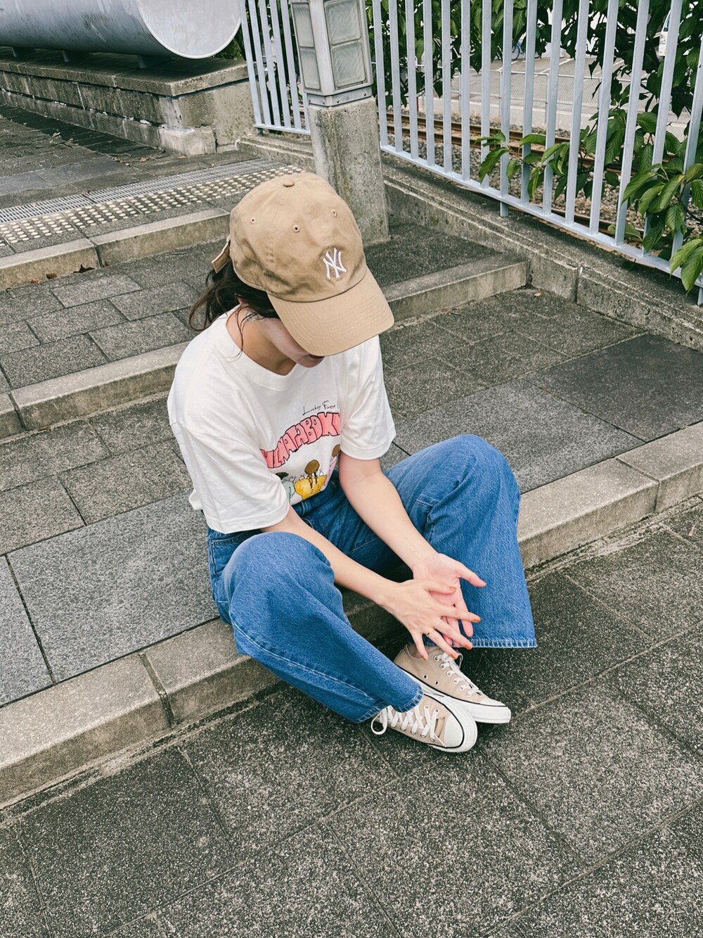 ブルー系のデニムパンツ、ベージュ系のスニーカー、ホワイト系のTシャツ/カットソーを着用したレディースの夏コーディネートの4枚目の写真