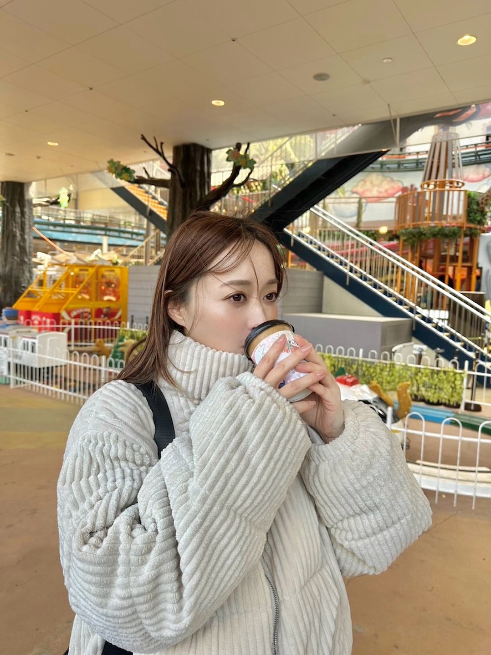 ブラック系のショルダーバッグ、ブラウン系のスラックス、ブラック系のスニーカーを着用したレディースの冬コーディネートの3枚目の写真