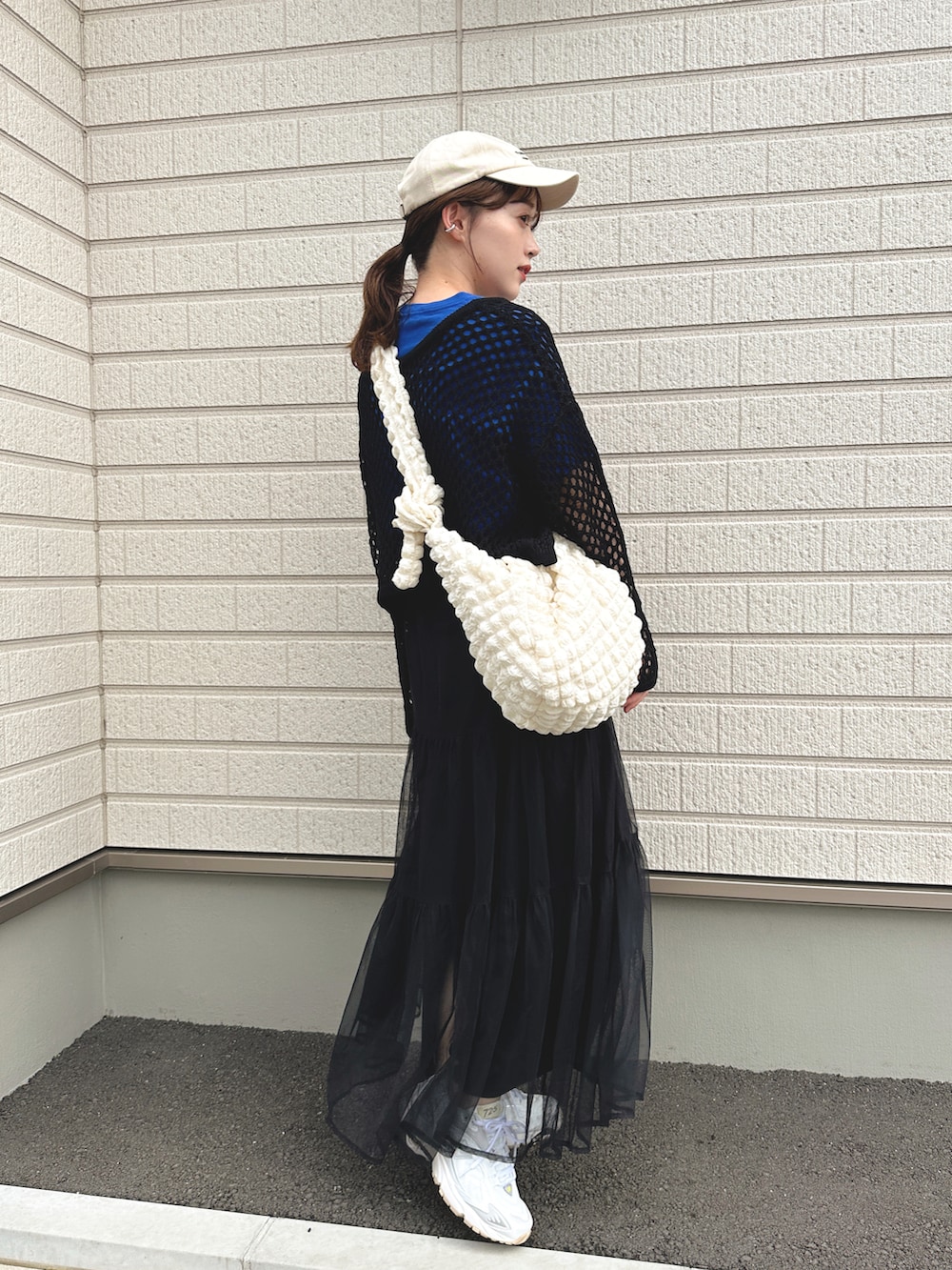 ブルー系のTシャツ/カットソー、ブラック系のスカート、ホワイト系のスニーカーを着用したレディースの春コーディネートの2枚目の写真