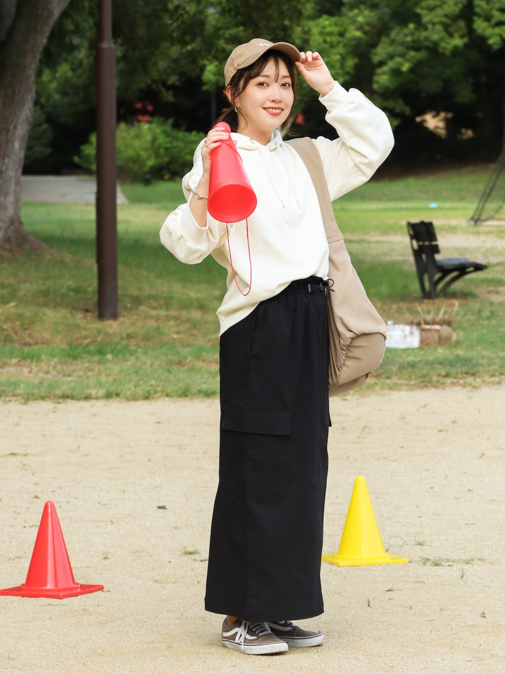 ブラック系のスカート、ホワイト系のパーカー、ベージュ系のバッグを着用したレディースの秋コーディネートの3枚目の写真