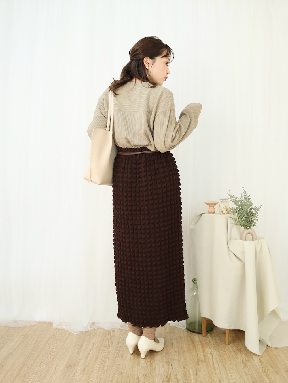 ベージュ系のトップス、ブラウン系のスカート、ホワイト系のショルダーバッグを着用したレディースの冬コーディネートの2枚目の写真