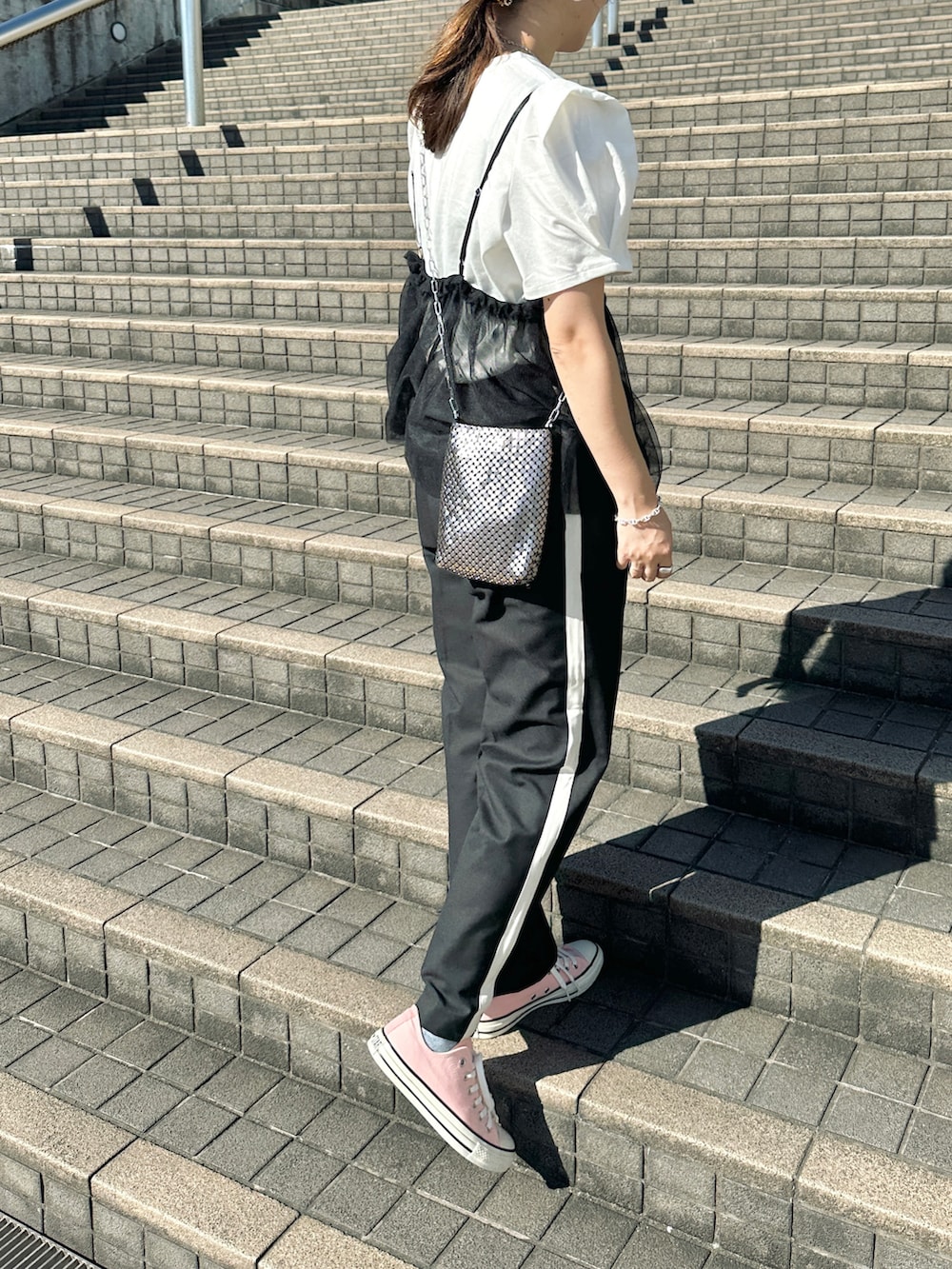 ホワイト系のTシャツ/カットソー、ブラック系のその他パンツ、シルバー系のショルダーバッグを着用したレディースの夏コーディネートの5枚目の写真