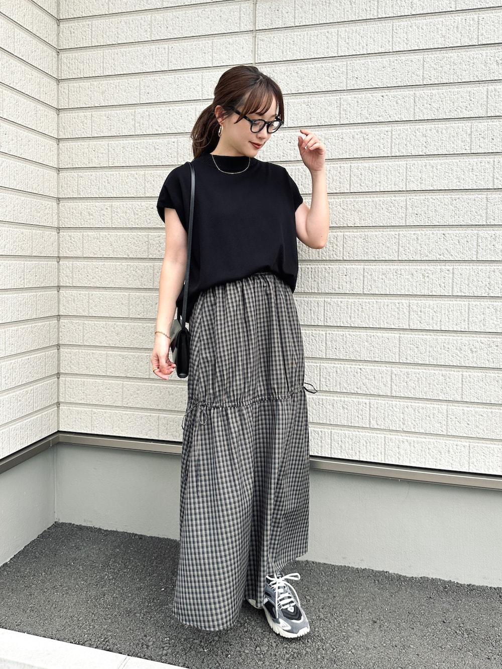 ブラック系のスカート、ブラック系のトップス、ブラック系のショルダーバッグを着用したレディースの夏コーディネートの2枚目の写真