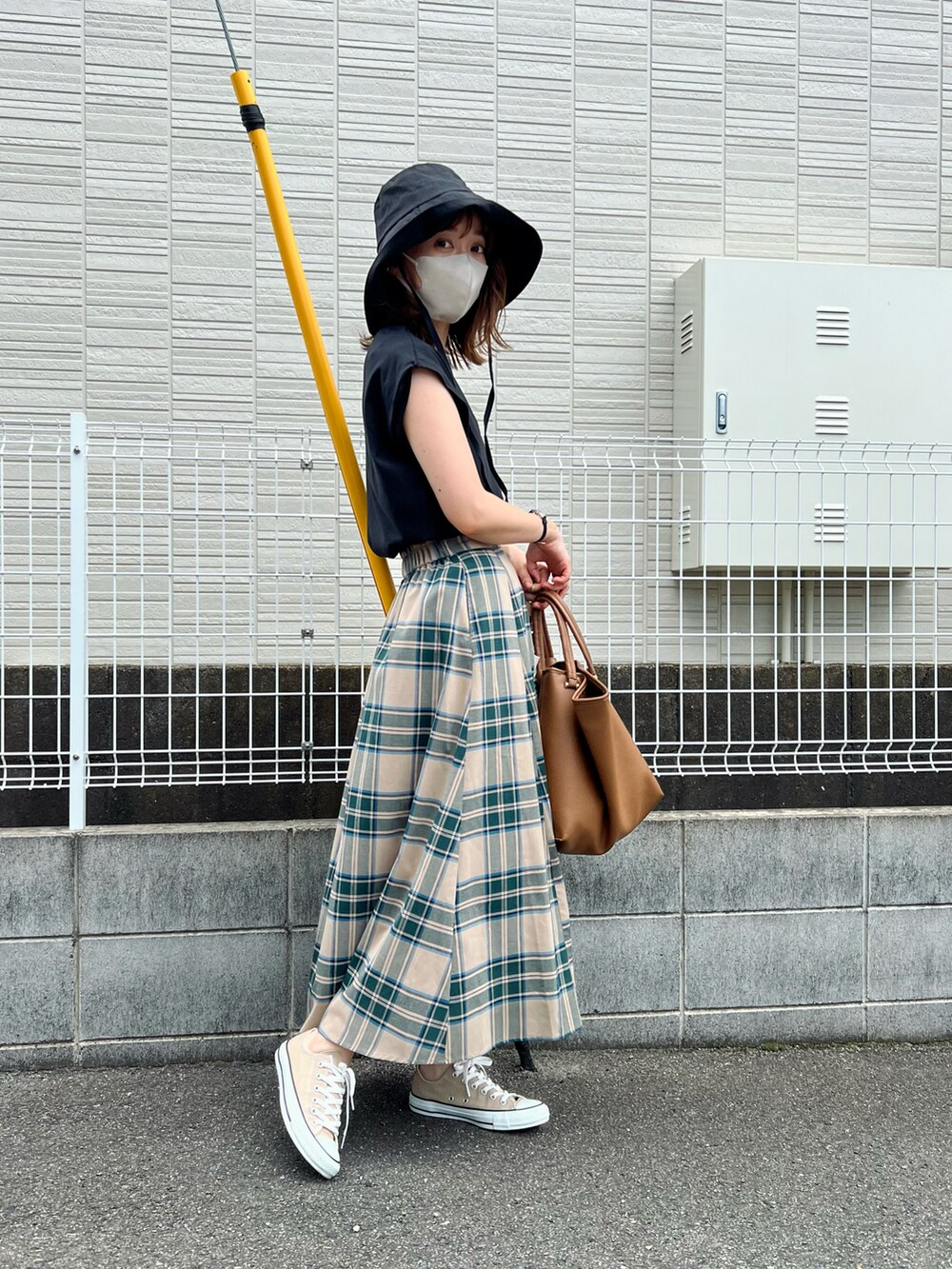 ブラウン系のバッグ、ベージュ系のスカート、ブラック系のトップスを着用したレディースの夏コーディネートの2枚目の写真