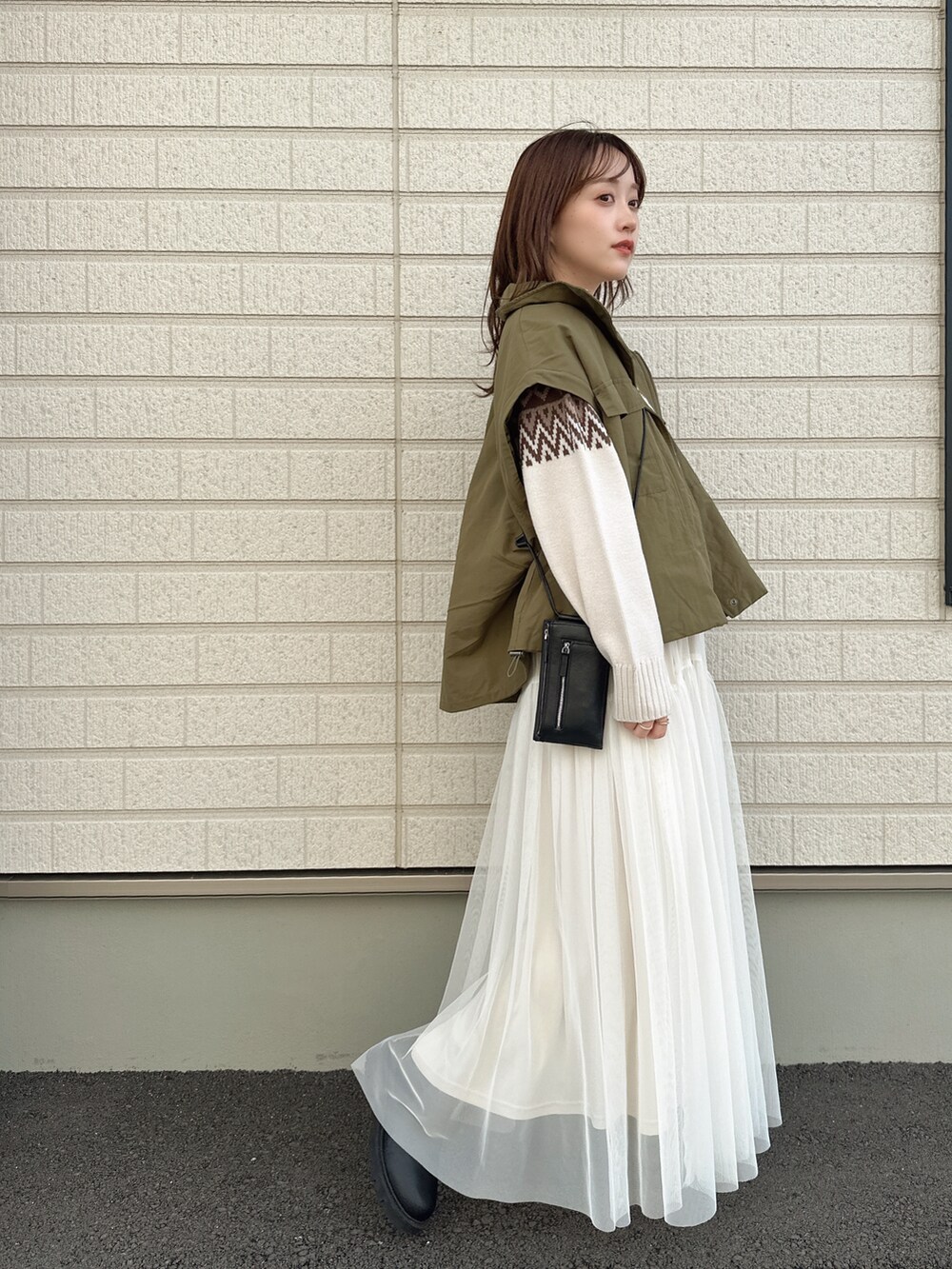 ホワイト系のニット/セーター、グリーン系のミリタリージャケット、ホワイト系のスカートを着用したレディースの秋コーディネートの2枚目の写真