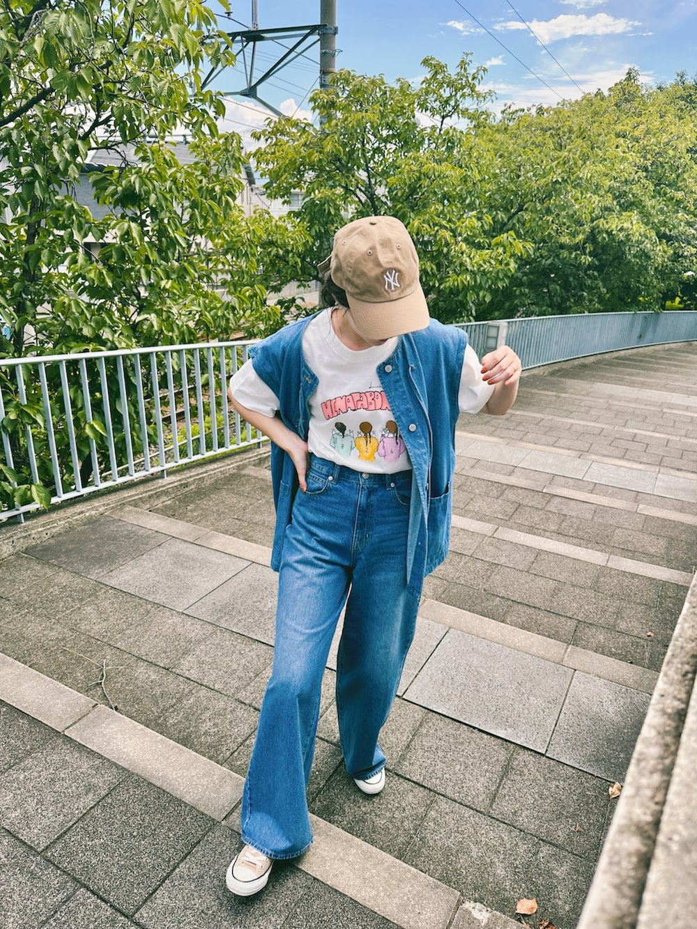 ブルー系のデニムパンツ、ベージュ系のスニーカー、ホワイト系のTシャツ/カットソーを着用したレディースの夏コーディネートの3枚目の写真