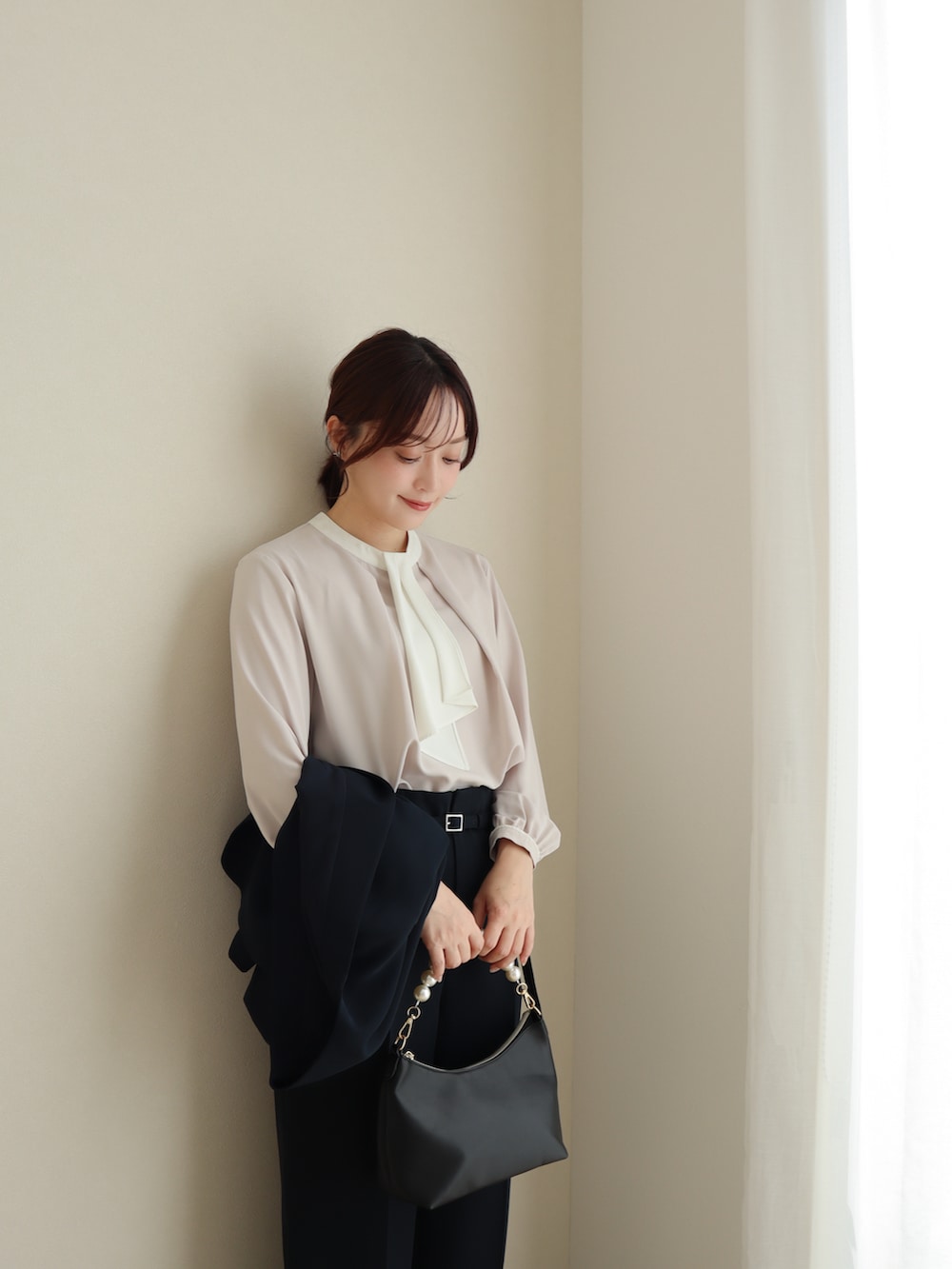 ブルー系のスーツセット、ピンク系のパンプス、ブラック系のバッグを着用したレディースの冬コーディネートの2枚目の写真