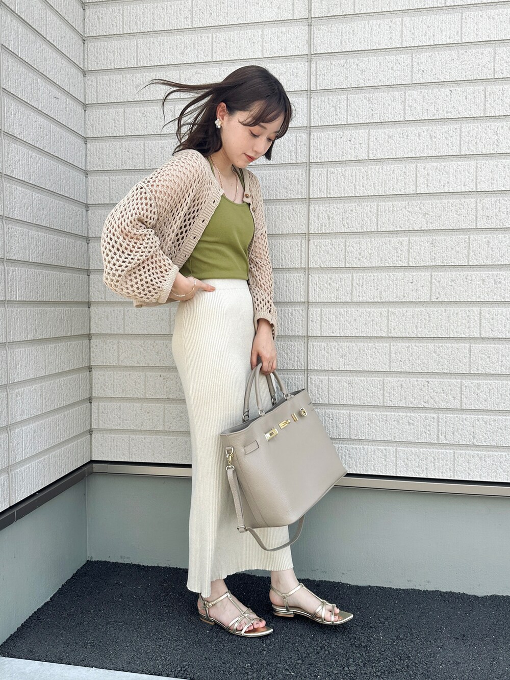 グリーン系のキャミソール、ベージュ系のスカート、ベージュ系のトートバッグを着用したレディースの春コーディネートの2枚目の写真