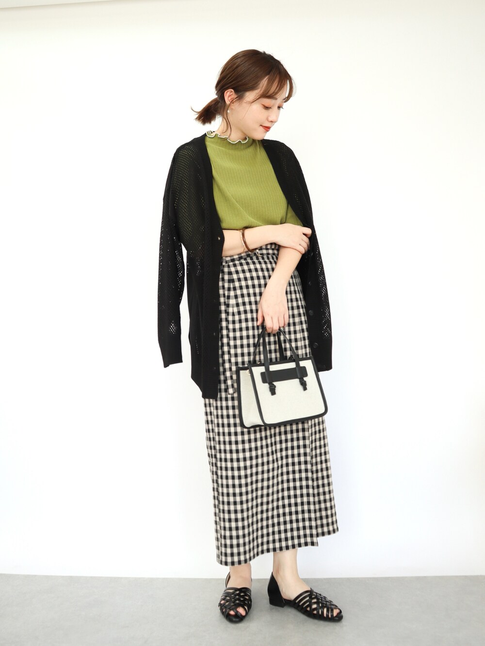 グリーン系のトップス、ブラック系のカーディガン/ボレロ、ブラック系のバッグを着用したレディースの春コーディネートの2枚目の写真