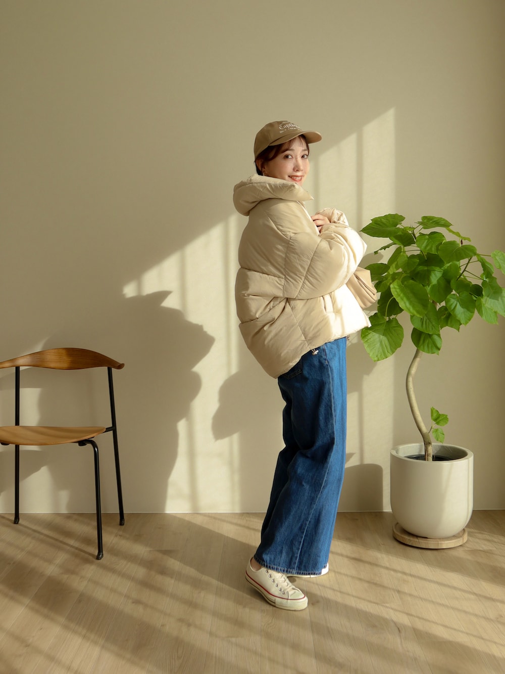 ベージュ系のジャケット/アウター、ベージュ系のハンドバッグ、ブルー系のデニムパンツを着用したレディースの冬コーディネートの2枚目の写真