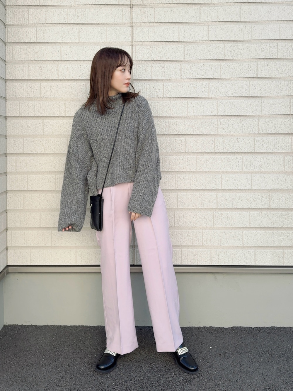 ピンク系のスラックス、ブラック系のローファー、ブラック系のショルダーバッグを着用したレディースの冬コーディネートの2枚目の写真