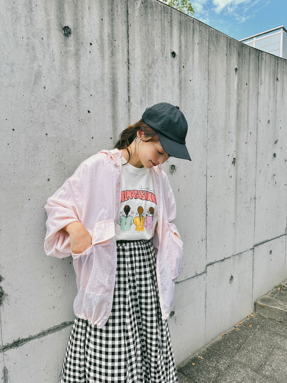 ブラック系のスカート、ピンク系のナイロンジャケット、ホワイト系のTシャツ/カットソーを着用したレディースの夏コーディネートの2枚目の写真