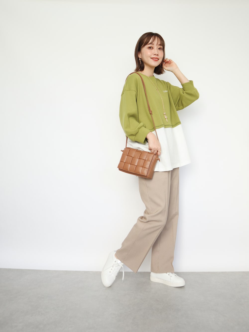 グリーン系のトップス、ベージュ系のパンツ、ブラウン系のバッグを着用したレディースの春コーディネートの3枚目の写真